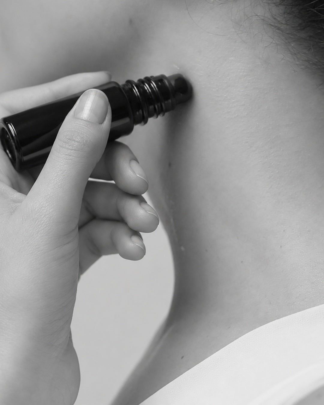 Una mano applica il roll-on MONOM sul collo